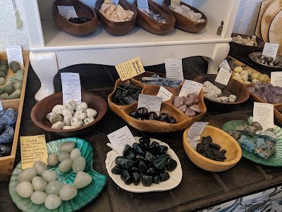 Table display of various crystals like bloodstone, jade, obsidian and their healing properties.