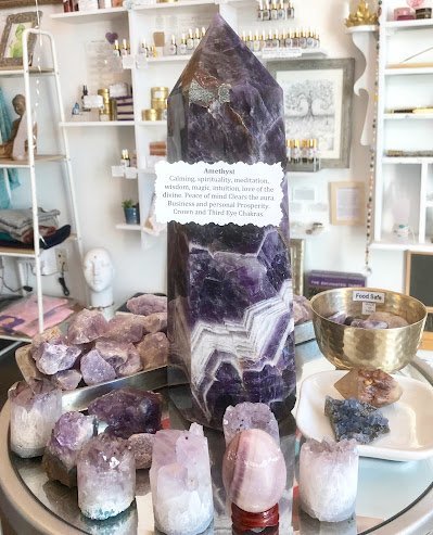 Amethyst tower labeled with spiritual properties and surrounded by amethyst and quartz with multiple points