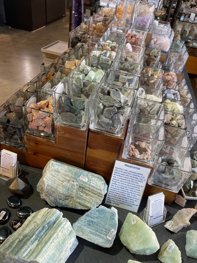 Large polished rose quartz bowl on white pedestal with mineral specimens in background