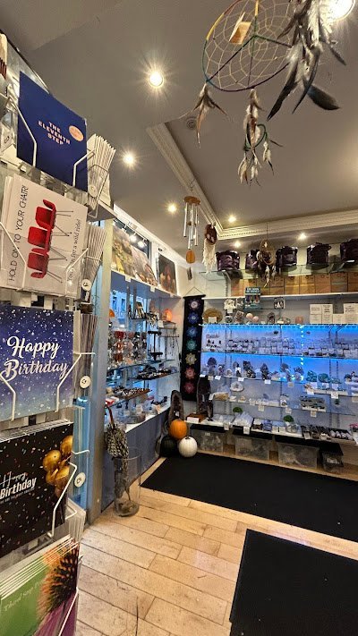Modern metaphysical boutique interior with dreamcatcher decor, blue LED-lit display cases, and organized crystal inventory