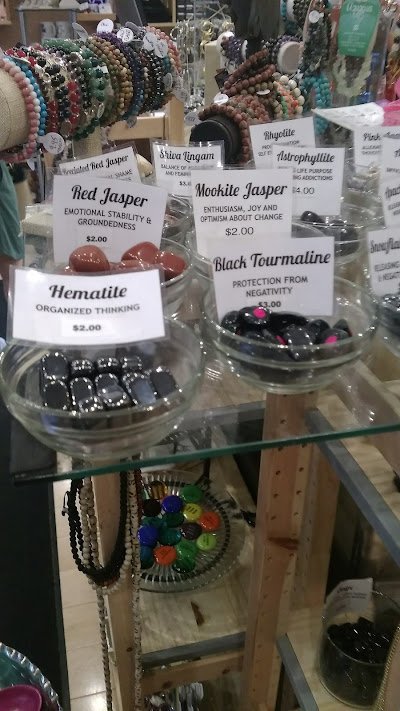 Display of labeled tumbled stones in glass bowls including red jasper, blue lingham, mookite jasper, hematite, and black tourmaline