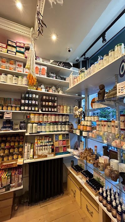 Modern shop interior with white shelving displaying spiritual products, herbs, candles, and packaged goods