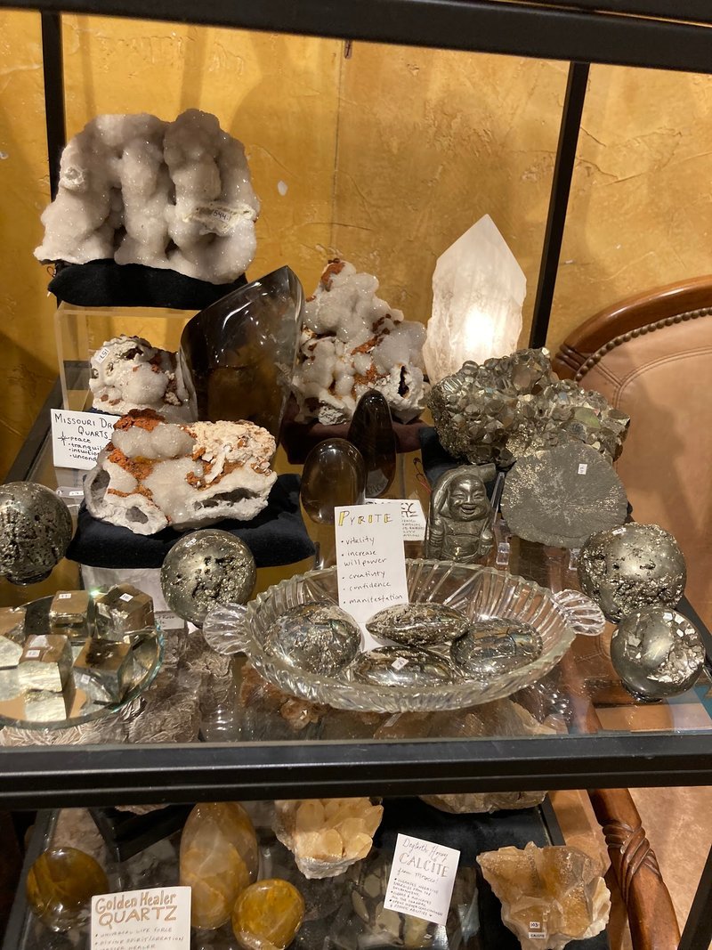 Display case with pyrite specimens, crystal carvings, and white quartz clusters