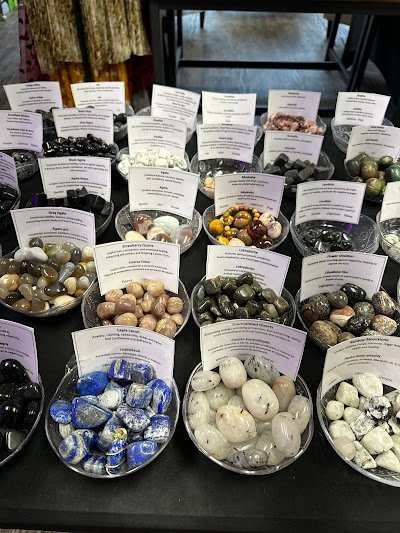 Wooden shelving displaying raw minerals, tumbled stones in wooden bowls, and labeled specimens