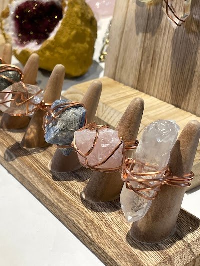 Modern spiritual boutique with purple walls, white seating, and organized crystal displays on metal shelves