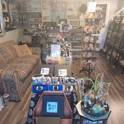 Modern boutique with round wood display table, rose quartz towers, and black metal shelving