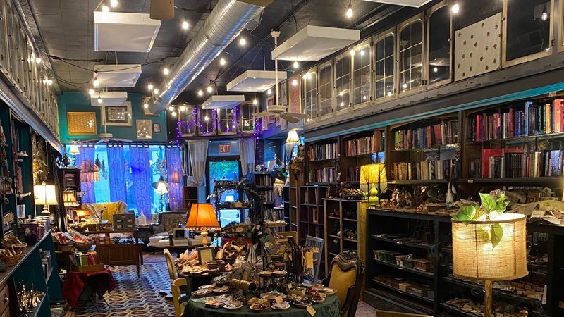 Wooden shelves displaying chakra candles with colorful labels and glass jars of herbs