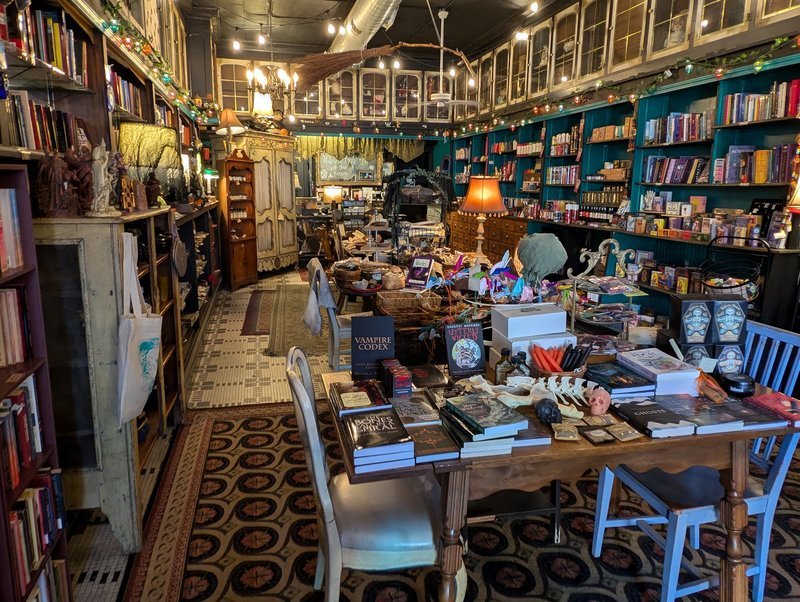 Corner glass display case with large quartz clusters, green fluorite towers, and rose quartz against purple wall