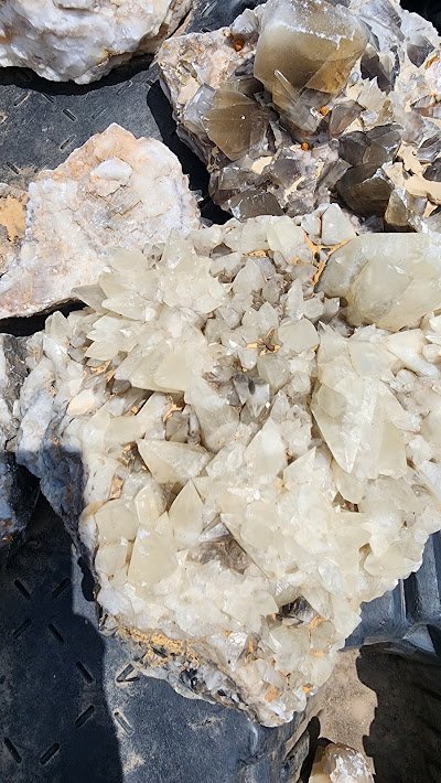Large white calcite crystal clusters and smoky quartz specimens
