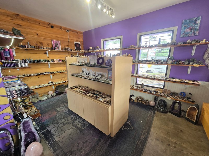 Store interior with purple walls and wooden shelving displaying crystals and minerals
