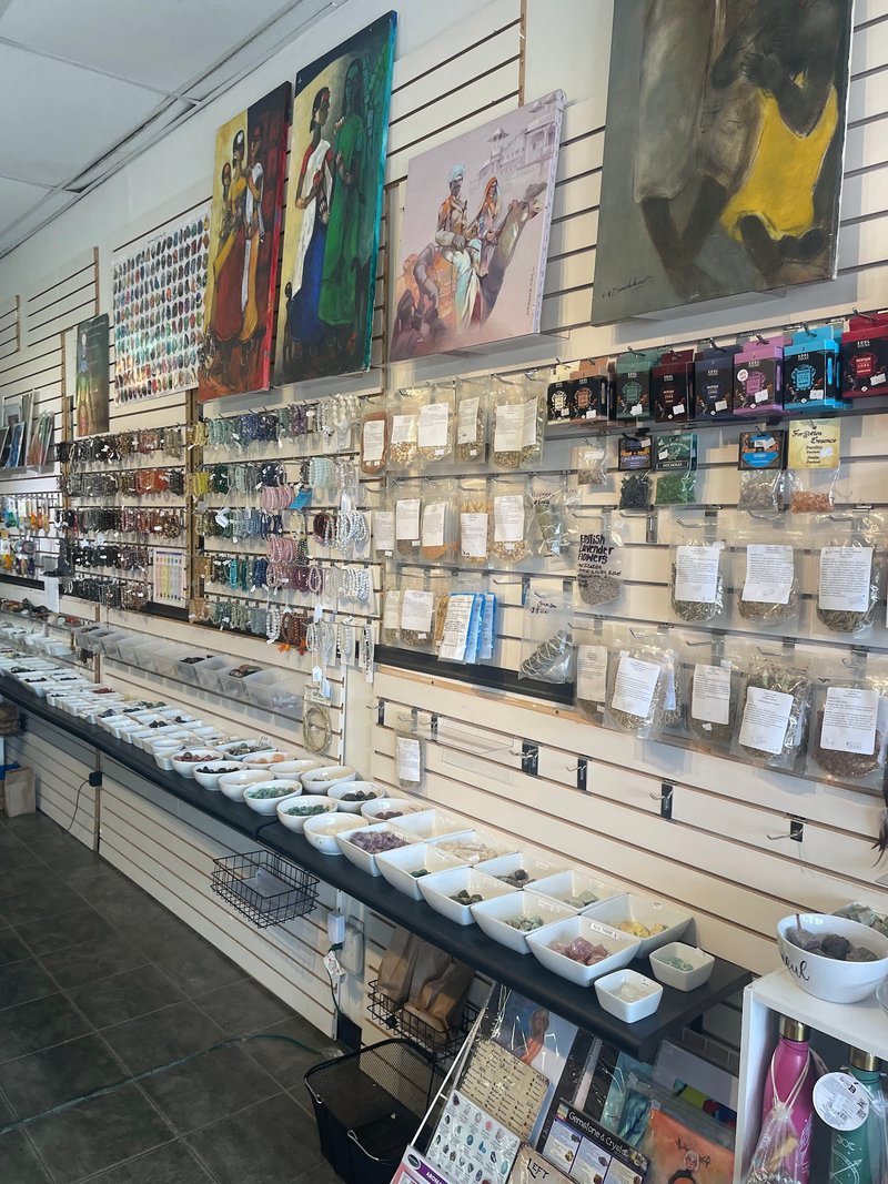 Retail wall display with crystals, jewelry, and metaphysical supplies organized in white bins