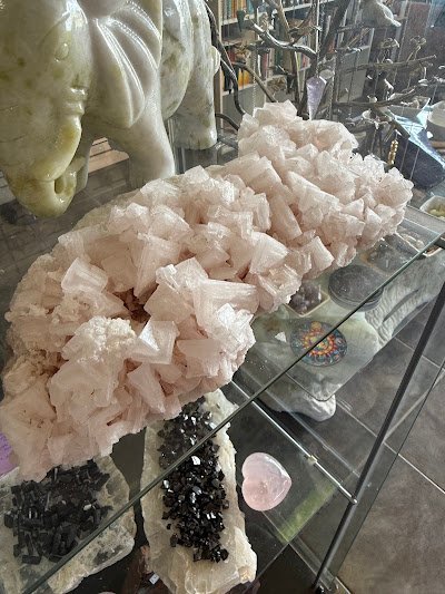 Large pink halite crystal cluster specimen on glass display