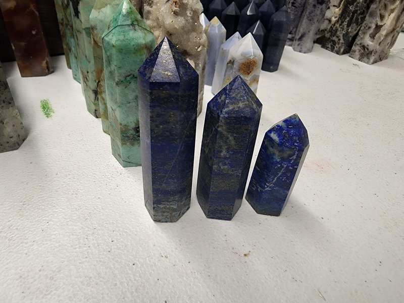 Three polished lapis lazuli towers with deep blue color and gold pyrite inclusions