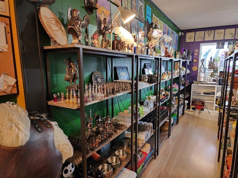 Metaphysical shop interior with green shelving displaying spiritual tools, crystals, and decorative items