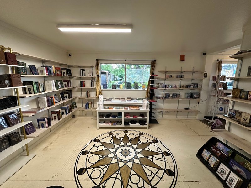 Bright room with floor mandala art, white shelving, and spiritual books