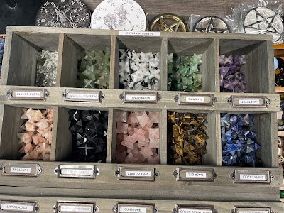 Wooden display organizer with tumbled stones sorted by crystal type and labeled
