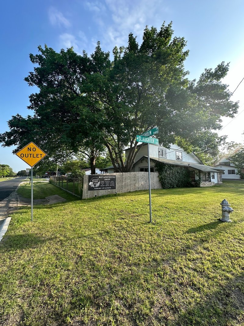 Exterior view of shop building with large tree and no outlet sign